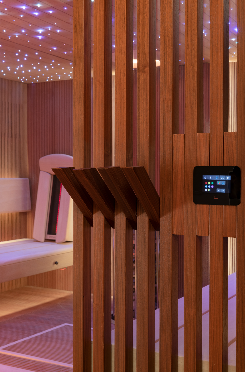 Wooden sauna with slatted walls and a control panel.