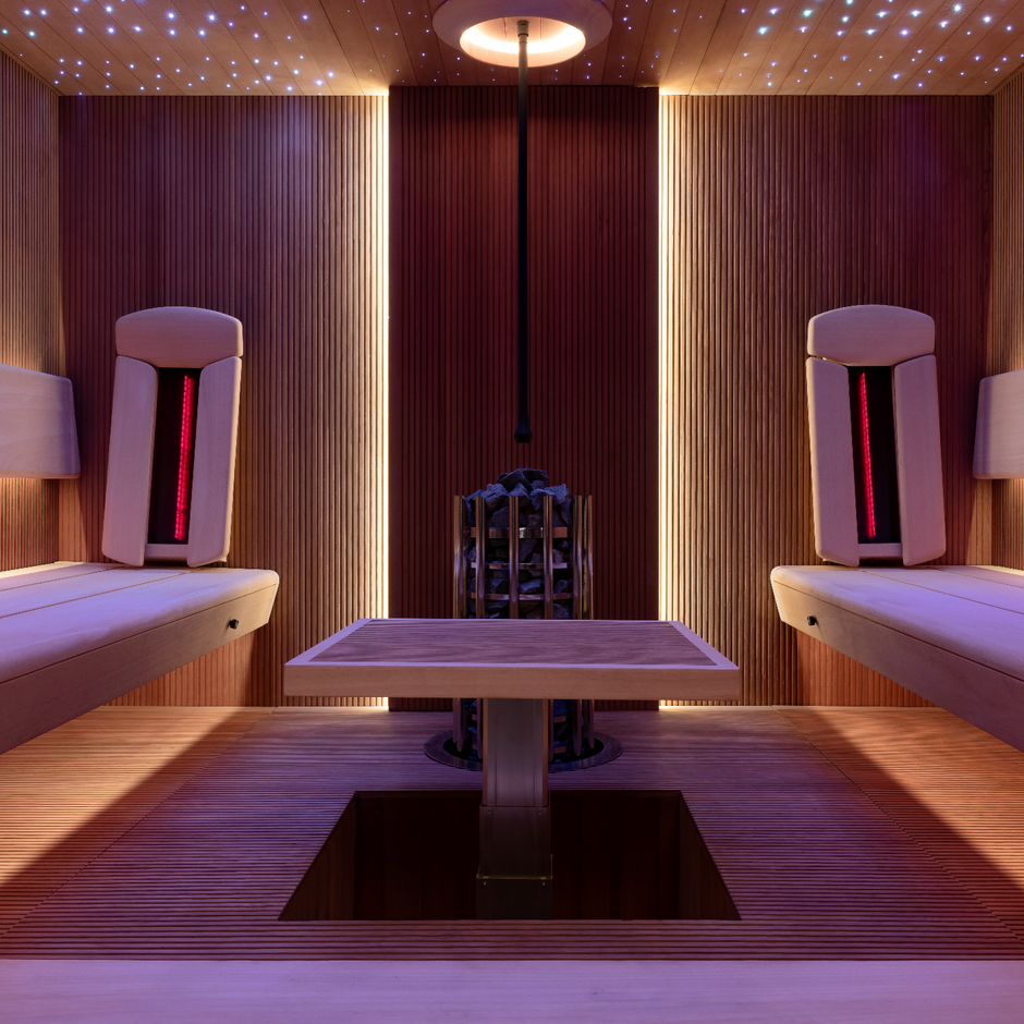 Modern luxury sauna interior featuring symmetrical wooden benches, soft ambient lighting, star-lit ceiling, and central heater — a refined wellness space crafted by Haus of Heat.