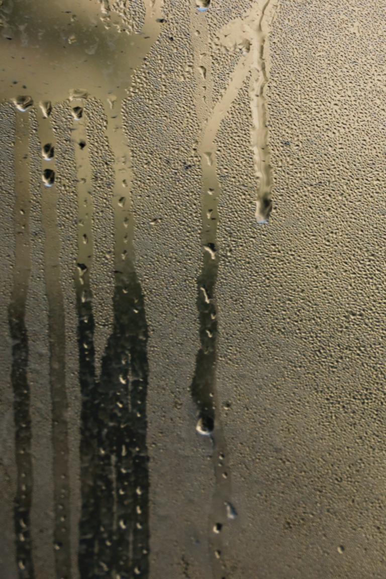 Foggy glass surface with water droplets and streaks in steam room