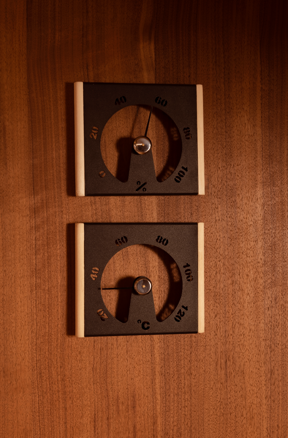 Two wooden thermometers and hygrometers on a wooden surface