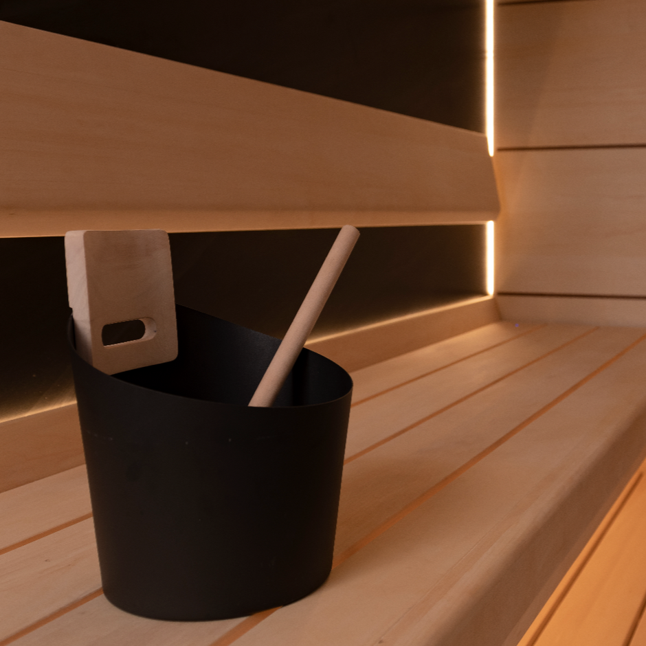 Wooden sauna interior with a black bucket and plant