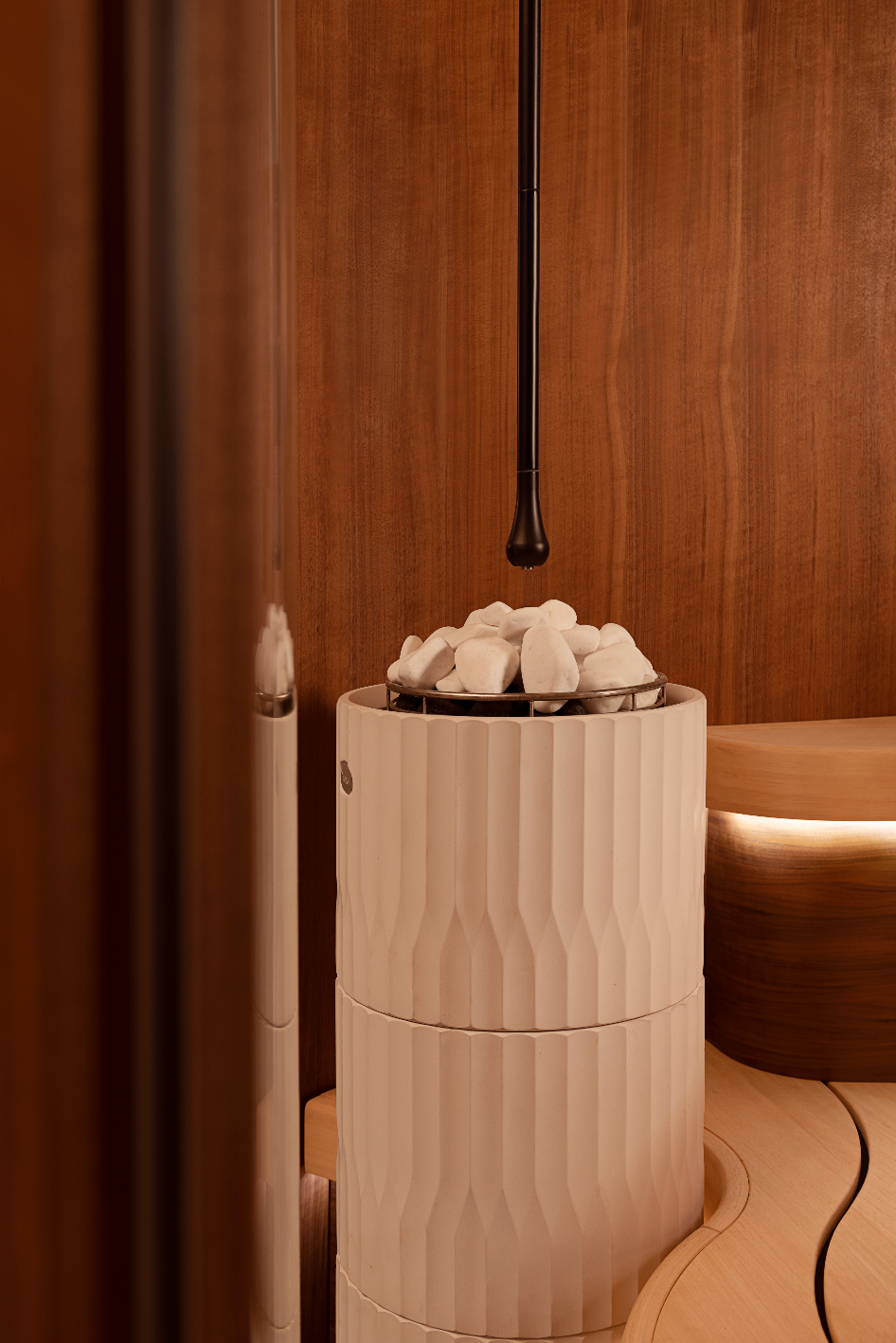 Modern Sauna stove with cylindrical light fixture on a wooden background