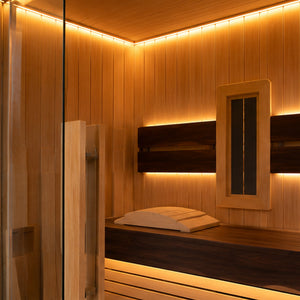 A warm, modern wooden sauna interior with tiered wooden benches, a glass door, and ambient LED lighting along the walls and ceiling.