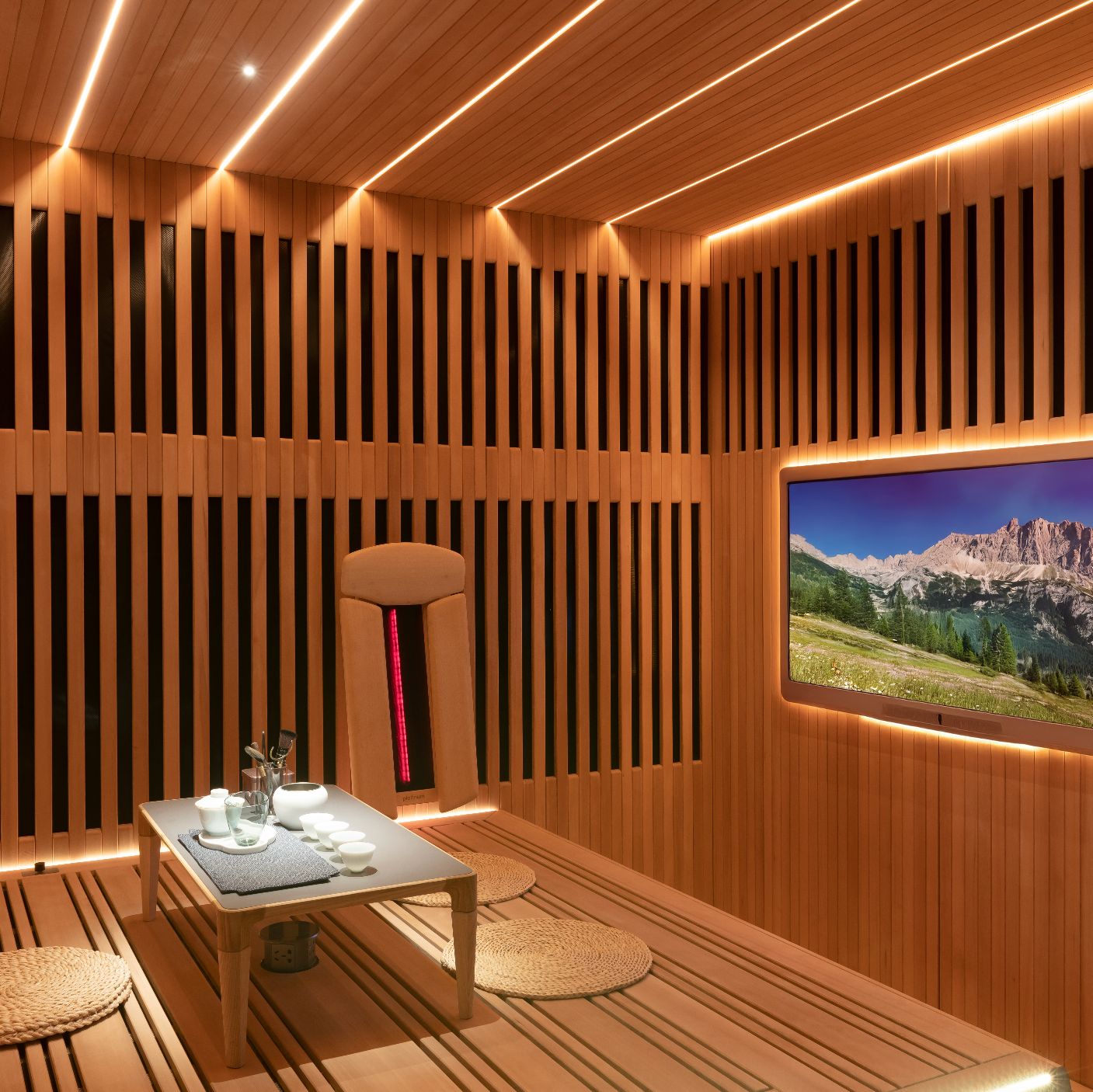 Wooden sauna interior with a TV displaying a mountain landscape.
